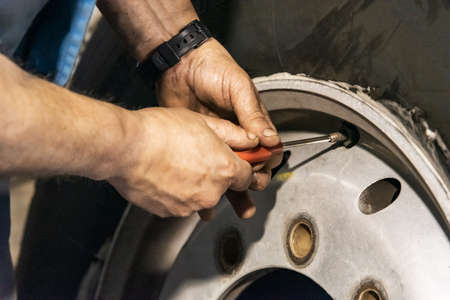 Tire workshop operator placing valve on wheel.の写真素材