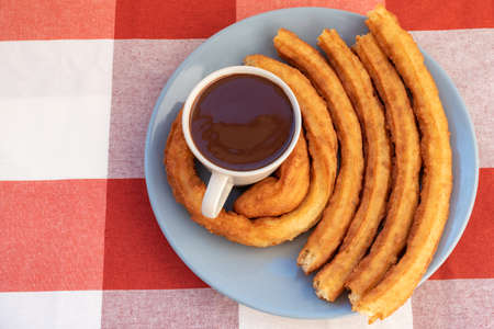 Plate with a cup of chocolate and churros surrounding the cup, breakfast or snack in Andalusia, Spain.の写真素材