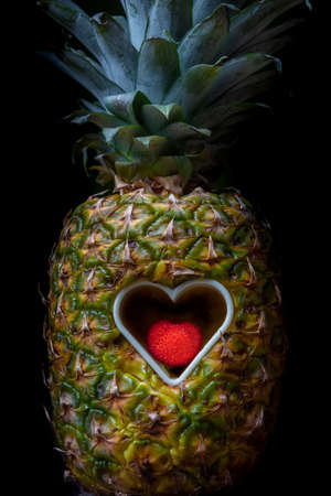 Pineapple with a heart-shaped opening in its center with a ripe madrone inside.の写真素材