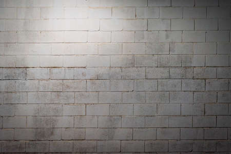 White block wall aged by humidity and illuminated with overhead light. Background.の写真素材