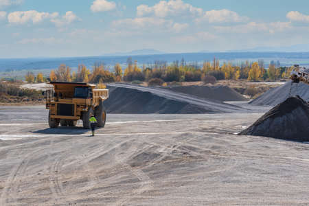 Driver walking towards a large dump truck for quarry work.