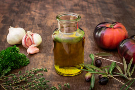 Bottle with extra virgin olive oil along with some tomatoes, garlic and olives on their branches.の写真素材