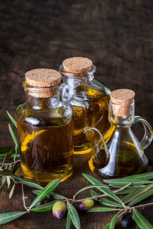 Bottle with extra virgin olive oil next to some olives on their branches.の写真素材