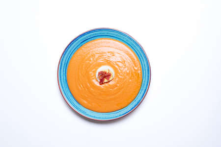 Round plate with salmorejo on a white background, accompanied with egg and ham.の写真素材