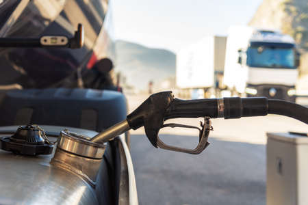 Truck refueling diesel at a highway gas station, close-up of the nozzle inserted in the vehicle's tank.の写真素材