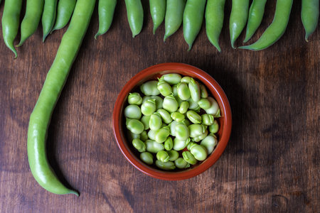 Fresh broad beans next to a clay plate with its fruitの写真素材
