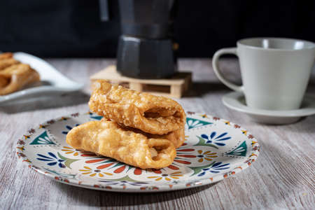 Plate with pestiÃ±os next to a cup of coffee and a pot, typical sweet of Holy Week.