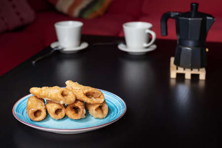 Plate with pestiÃ±os on a table with cups of coffee next to a coffee pot.の写真素材