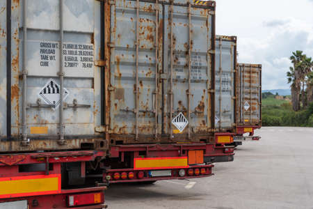 Rear view of several trucks with containers labeled with dangerous goods, ADR.