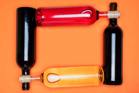 Several bottles of wine, red, white and rosÃ©, crossed with each other, on an orange background.の写真素材