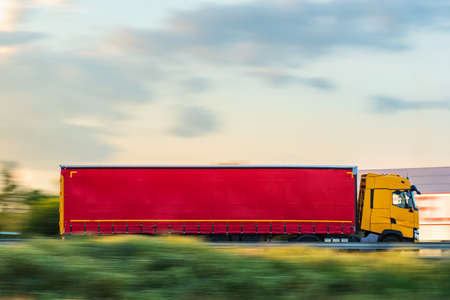 Truck with tarpaulin semi-trailer for general cargo traveling fast on the highway.の写真素材