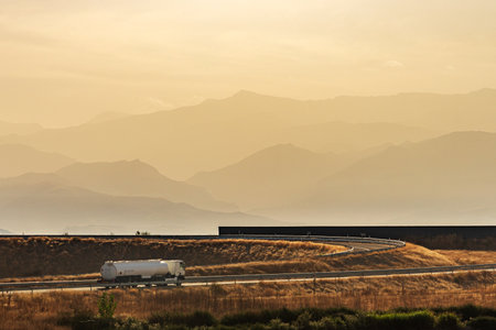 Fuel tanker truck driving along a freeway access with a background of mountains.の写真素材
