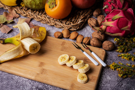 Banana of Canarian origin cut into slices on a wooden board, accompanied by tropical fruits such as pitahaya, persimmon and custard apple.の写真素材