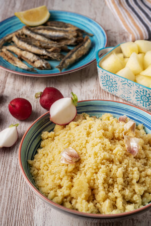 Plate of migas, traditional Spanish food, accompanied with radishes, fish and melon on a wooden table.の写真素材