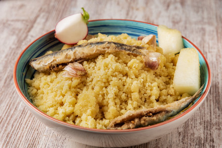 Plate of migas, traditional Spanish food, accompanied with radishes, fish and melon on a wooden table.の写真素材
