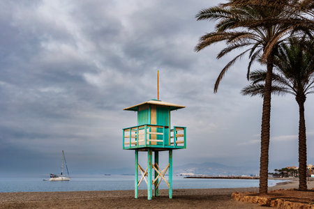 Guardhouse of the beaches in Torrenueva Costa, Granada, next to some palm trees and a sailboat in the Mediterranean Sea.の写真素材