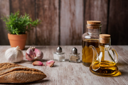 Extra virgin olive oil in an oil can and in a small bottle, on a wooden table.の写真素材