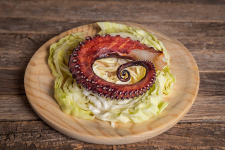 Dried octopus leg on shredded cabbage leaves, on a wooden plate.の写真素材