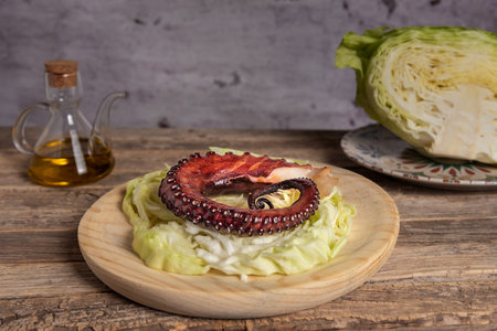 Dried octopus leg on shredded cabbage leaves, on a wooden plate next to an oil can and a piece of cabbage.の写真素材