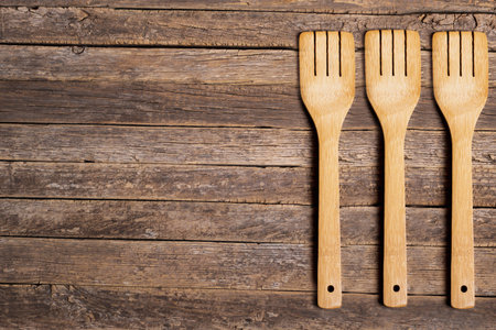 Background of rustic and aged wooden slats with three wooden forks on one side.の写真素材