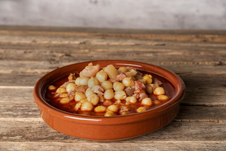Clay dish with tripe and chickpeas, on an old wooden background.の写真素材