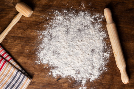 Kitchen table with sprinkled flour next to a rolling pin and a wooden hammer, utensils for working the dough.の写真素材