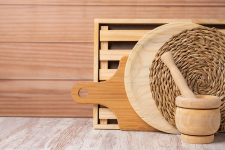 Kitchen utensils, trivet, wooden plate, chopping board, mortar and bread board, arranged decoratively with light wood background.の写真素材