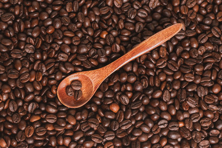 Wooden spoon with roasted coffee beans on a background of coffee beans.の写真素材