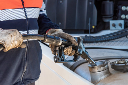 Truck driver with a pump nozzle in his hands filling the vehicle's fuel tank, Close-up.の写真素材