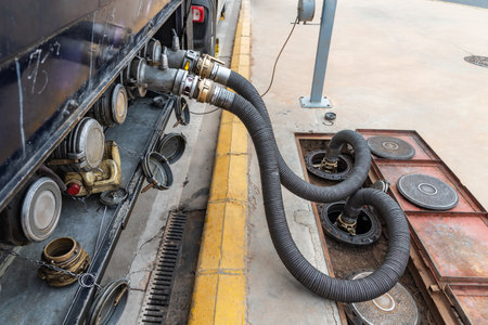 Fuel tanker truck unloading at a service station, unloading with two hoses and different products at the same time. Close-up.の写真素材