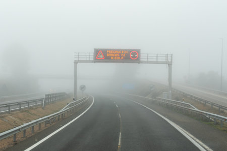 Illuminated sign on the highway with the legend Caution, fog banks.の写真素材