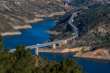 Rules Reservoir in Granada with the road that borders it and crosses over concrete and metal bridges, with a truck driving over the dam.の写真素材