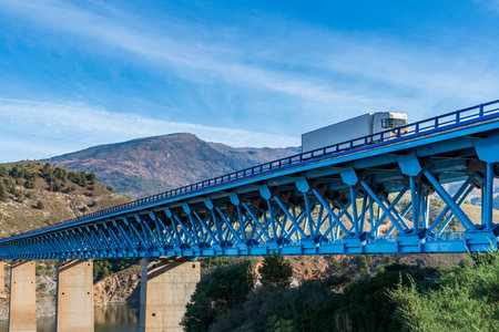 Truck with a refrigerated semi-trailer driving on a metal bridge with concrete bases.の写真素材