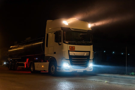 Tanker truck with dangerous goods on a foggy night with high beam lights on. Close-up.の写真素材