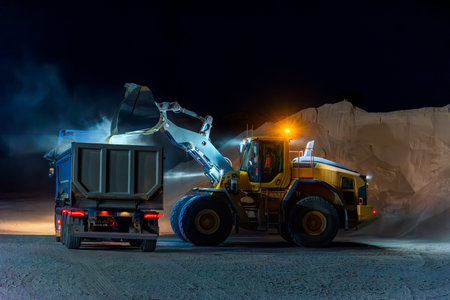 Heavy construction and mining machinery loading a dump truck with gravel in a quarry on the night shift. Close-up.の写真素材