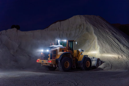 Heavy construction and mining machinery filling the bucket of a stockpile during the night shift. Close-up.の写真素材