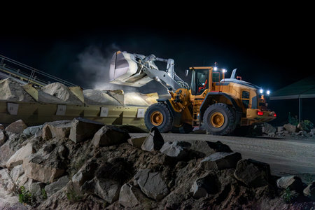 Heavy construction and mining machinery unloading gravel into silos on the night shift. Close-up.の写真素材