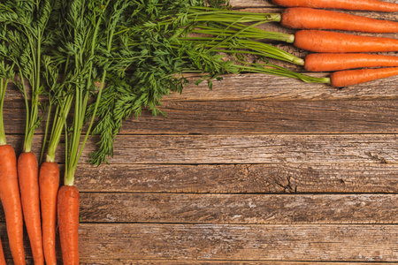 Background of old wooden planks with carrots with their green stem on the sides.の写真素材