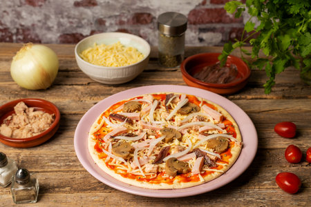 Plate with a pizza ready to bake, with vegetables, tuna, cooked ham and anchovies.の写真素材