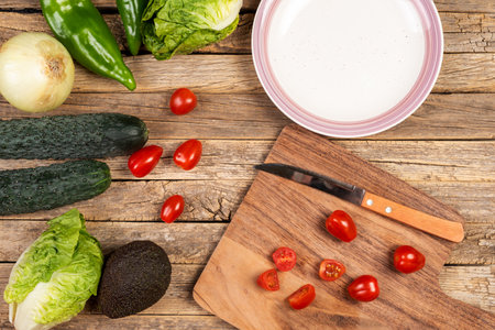 Vegetables and fruits next to a plate and a cutting board to prepare a salad.の写真素材