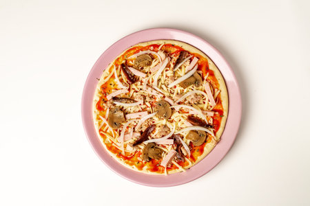 Plate with a pizza ready to bake, with vegetables, tuna, cooked ham and anchovies.の写真素材