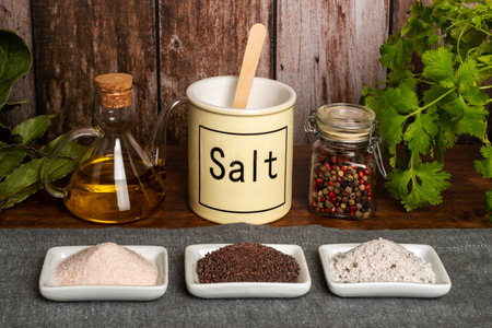 Salt jar together with small dishes with different types of salt, black, pink and seasoned with truffle.の写真素材