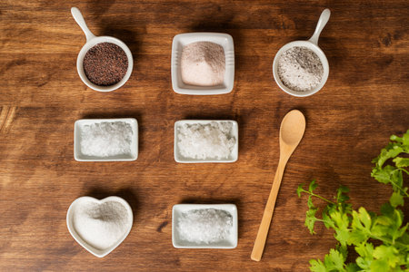 Small jars with different types of salt, black and pink from the Himalayas, normal, coarse, flakes, seasoned with truffle and from the Blackwater river (UK), on a wooden background,の写真素材