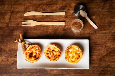 Pasteis de nata, also called de Belem, typical sweet from Lisbon, Portugal, several pastries on a long plate and cinnamon.の写真素材