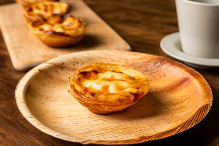 Pasteis de nata, also called de Belem, a typical sweet from Lisbon, Portugal, a cake on a plate next to a cup of coffee.の写真素材