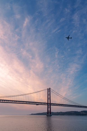 April 25 Bridge at sunrise with a plane flying over, Lisbon.の写真素材