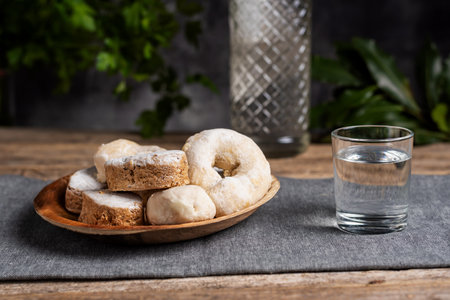 Shortbread, wine donuts and puff pastries on a wooden plate and next to a small glass with anise.の写真素材