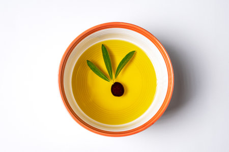 Bowl with virgin olive oil with an olive inside with three olive leaves.の写真素材