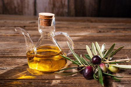 Close-up of an oil jug with virgin olive oil next to a tree branch with olives.の写真素材