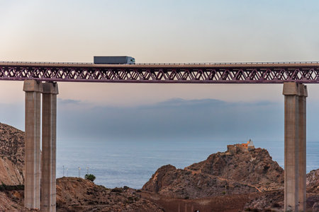 Truck driving on a high bridge, under a lighthouse and the Mediterranean Sea in the background, Almeria.の写真素材